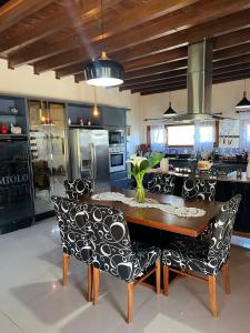 uma cozinha com uma mesa de madeira e cadeiras pretas e brancas em Quinta da Serra - Onde o charme se mistura com a natureza em Rancho Queimado