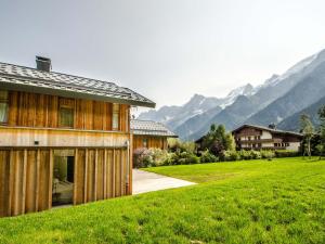 夏蒙尼-勃朗峰Chalet contemporain aux Houches, près des pistes, 6 chambres, WiFi, jardin, grille-pain - FR-1-343-179的田野中的一栋房子，背景是群山
