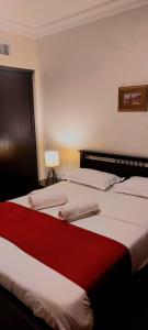 a bedroom with two beds with red and white sheets at Tamrah Suites Hotel in Amman