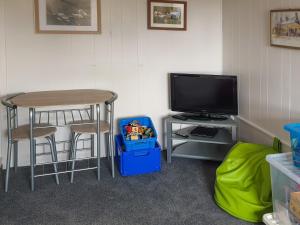LlanfaelrhysにあるHendyのテーブル、テーブル、テレビが備わる客室です。