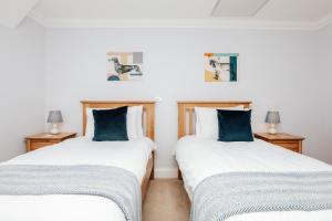 2 Einzelbetten in einem Zimmer mit blauen Kissen in der Unterkunft Olive Tale in Henley on Thames