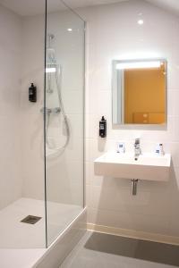 La salle de bains est pourvue d'un lavabo et d'une douche. dans l'établissement ibis budget Lunel Porte de Camargue, à Aimargues