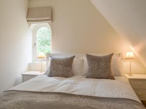 a bed with white sheets and pillows in a bedroom at Brookside Cottage in Burley