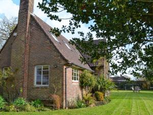 a brick house with a chimney and a grass yard at Brookside Cottage in Burley