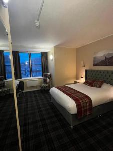 una camera d'albergo con un grande letto e finestre di Britannia Inn Glasgow a Glasgow