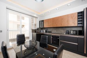 a kitchen with black cabinets and a table and chairs at Stylish 2 bedroomed apartment Gzira (UPDATED PICS) in Il-Gżira