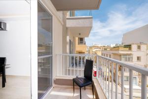 een balkon met een stoel en uitzicht op de stad bij Stylish 2 bedroomed apartment Gzira (UPDATED PICS) in Il-Gżira