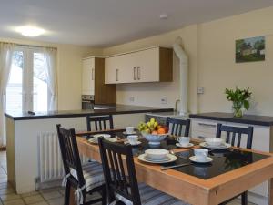 a kitchen with a wooden table with chairs and a dining room at Brookside Cottage in Forton