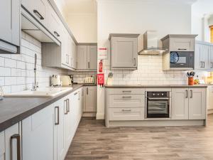 a kitchen with white cabinets and white appliances at Admirals Rest in Cromer