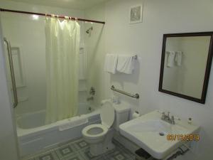 a bathroom with a toilet and a tub and a sink at Western Inn - Green River in Green River