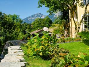 un giardino con parete in pietra e montagne sullo sfondo di Villa am Wappach a Bayerisch Gmain