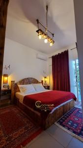 a bedroom with a large bed with a red blanket at Clockwise GuestRooms in Gjirokastër
