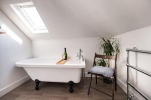 a bathroom with a white bath tub and a chair at Bright, Seaview Apartment, Beachfront, 3 bedrooms, 2 bathrooms, kid & dog friendly at The Lookout Broadstairs in Broadstairs