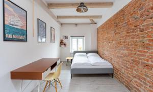 a brick wall in a room with a bed and a desk at myNEST Apartments RATAJCZAKA in Poznań