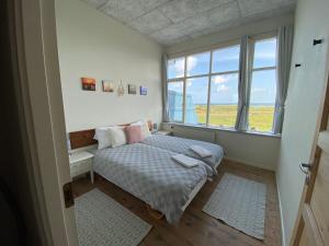 een slaapkamer met een bed en een groot raam bij Skærven Beachfront Apartments and Cottage in Nyborg