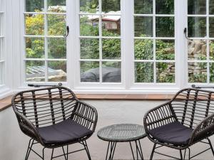 two chairs and a table in a room with windows at Haycraft Cottage in Langton Matravers