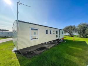 a tiny house sitting on top of a grass field at 8 Berth Caravan At Broadland Sands Holiday Park In Suffolk Ref 20140bs in Hopton on Sea