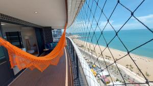 Un balcón con una hamaca naranja y vistas a la playa. en LINDO AP 3/4 FRENTE MAR LANDSCAPE, en Fortaleza