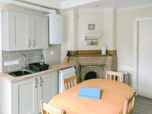 a kitchen with a table and a fireplace at Ivy-w40854 in Llanddona