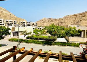 a wooden bench in front of a building with a mountain at one bedroom Modern Apartment Muscat Bay in Muscat