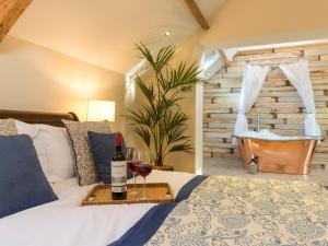 a bedroom with a bed with a bottle of wine and a tub at The Coach House in Ridingmill