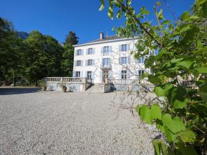 une grande maison blanche avec une allée en pierre dans l'établissement Domaine Clairfontaine Noyarey - Suites Junior, à Noyarey