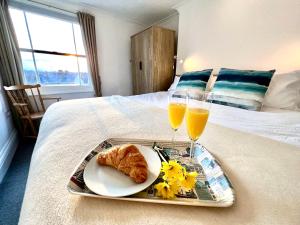 a tray with a plate of food and two glasses of orange juice at Bright, Seaview Apartment, Beachfront, 3 bedrooms, 2 bathrooms, kid & dog friendly at The Lookout Broadstairs in Broadstairs
