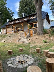une maison sur une colline avec un arbre et des bûches dans l'établissement Hamerská chaloupka, à Hlinsko