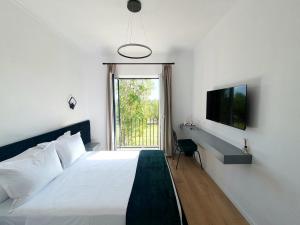 a bedroom with a bed and a tv and a window at Nerium Garden Inn Tirana Airport in Rinas