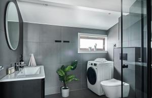 uma casa de banho com uma máquina de lavar roupa e um lavatório em Hatty's Habitat By Staysville em Stavanger