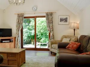 a living room with a couch and a sliding glass door at Trem Yr Ynys in Betws-y-coed