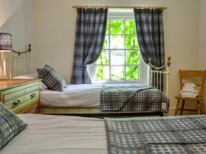 een slaapkamer met 2 bedden en een raam bij Trem Yr Ynys in Betws-y-coed