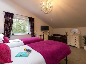 1 dormitorio con 2 camas y mantas moradas en The Haybarn en Ferndown