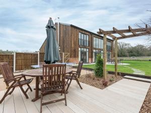 eine Holzterrasse mit einem Tisch und einem Sonnenschirm in der Unterkunft The Haybarn in Ferndown