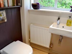 a bathroom with a toilet and a sink and a window at Brookside Cottage in Burley