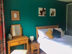 um quarto com uma parede verde com uma cama e um espelho em Townsend Pod em Greinton