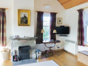 een woonkamer met een open haard en een televisie bij Tummel Cottage in Foss