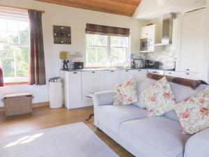 a living room with a white couch and a kitchen at Tummel Cottage in Foss