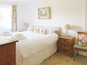 een slaapkamer met een bed met witte lakens en kussens bij Tummel Cottage in Foss