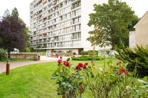 a large apartment building with a green yard with flowers at 2-pièces ensoleillé, 5 min du metro in Villejuif