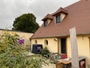 a house with a roof and a yard with flowers at Room in Guest room - bed and breakfast in the countryside near Beauvais airport in Auneuil