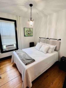 a bedroom with a large white bed with a chandelier at Centrally located East End & off-street parking in Portland