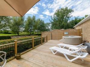 une terrasse en bois avec deux chaises longues et un bain à remous dans l'établissement 1 Luckington Stables-w8321, à Holcombe