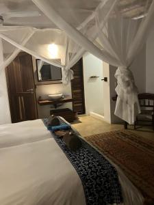 a bedroom with a white bed with a canopy at Ebony beach in Vilanculos