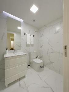 a white bathroom with a toilet and a sink at Vibrant Porto Apartments-Campo 24 Agosto in Porto