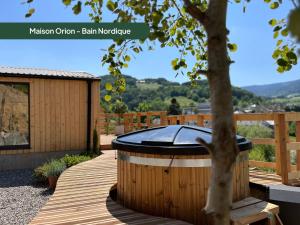 a hot tub on a wooden deck with a tree at Domaine des Constellations - Gîtes & Bains Nordiques in Orbey