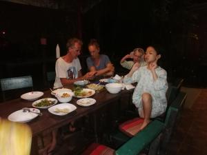 Milin Guesthouse في شيانج راي: مجموعة من الناس يجلسون حول طاولة يأكلون الطعام