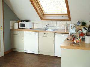 a kitchen with white cabinets and a sink and a window at Fleet Cottage in Portree