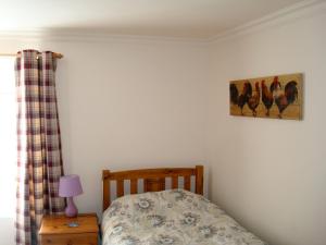 1 dormitorio con 1 cama y una foto de gallinas en la pared en Fleet Cottage, en Portree