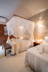 a bedroom with two beds and a canopy bed at Pousada Recanto do Sol in Trancoso